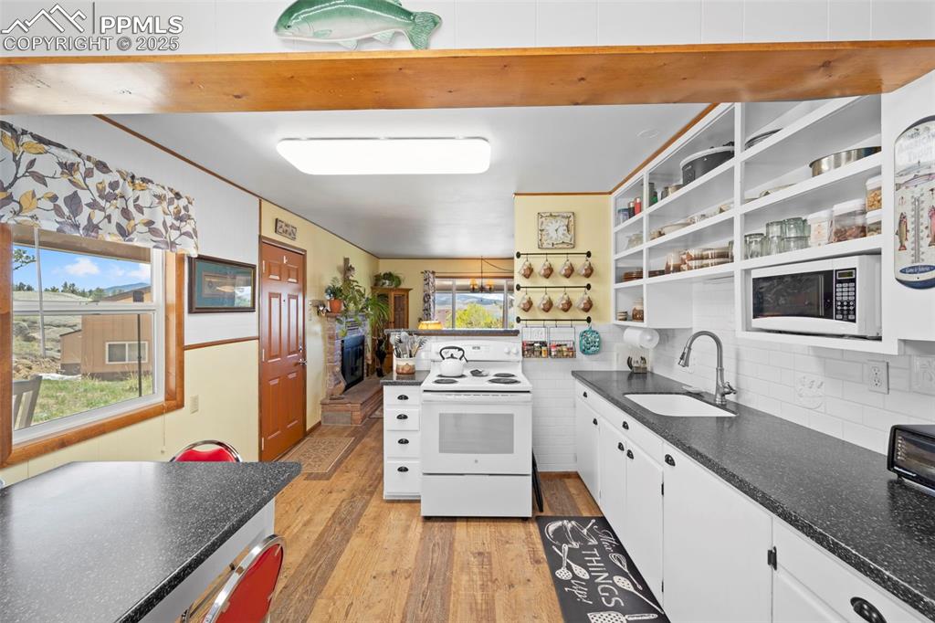 Image 17 of 31: Kitchen featuring white appliances, a sink, dark countertops, light wood fi