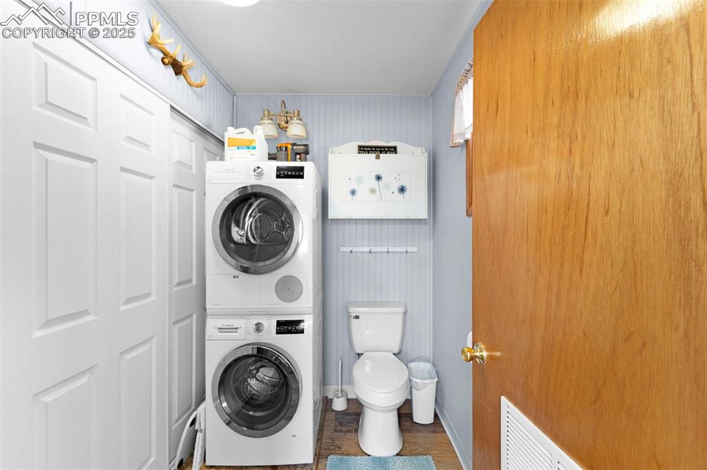 Image 18 of 31: Laundry room with stacked Bosch appliances and half bath combo. 