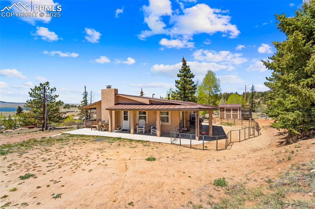 Image 23 of 31: Back of property with a chimney, a patio, metal roof, a standing seam roof,