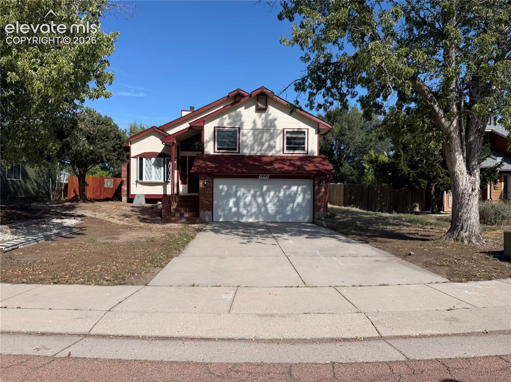 Image 1 of 21: Split-level residence featuring a brick and stucco exterior, an attached ga