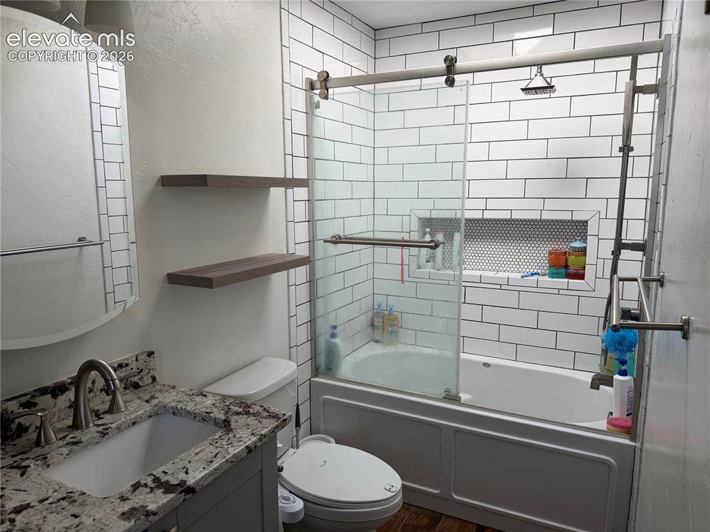 Image 14 of 21: Bathroom featuring a subway tile shower surround, sliding glass shower door