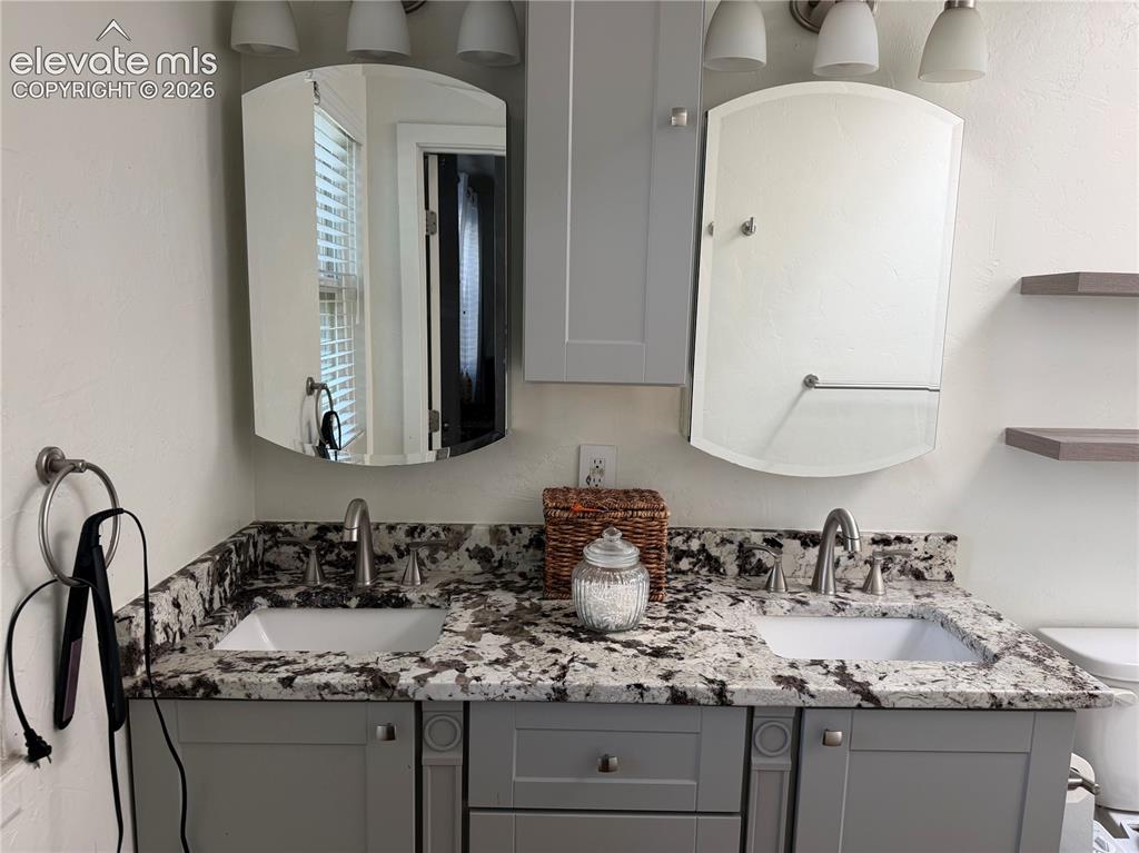 Image 15 of 21: Dual vanity with integrated sinks, speckled stone countertop, light gray ca