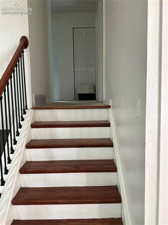 Image 16 of 21: Staircase featuring wood-finish treads and white risers