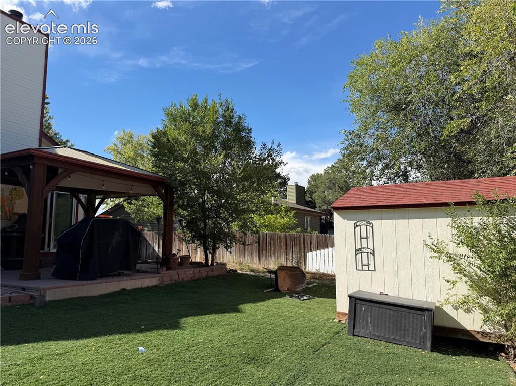 Image 18 of 21: Expansive backyard featuring a covered patio with string lighting, a manicu