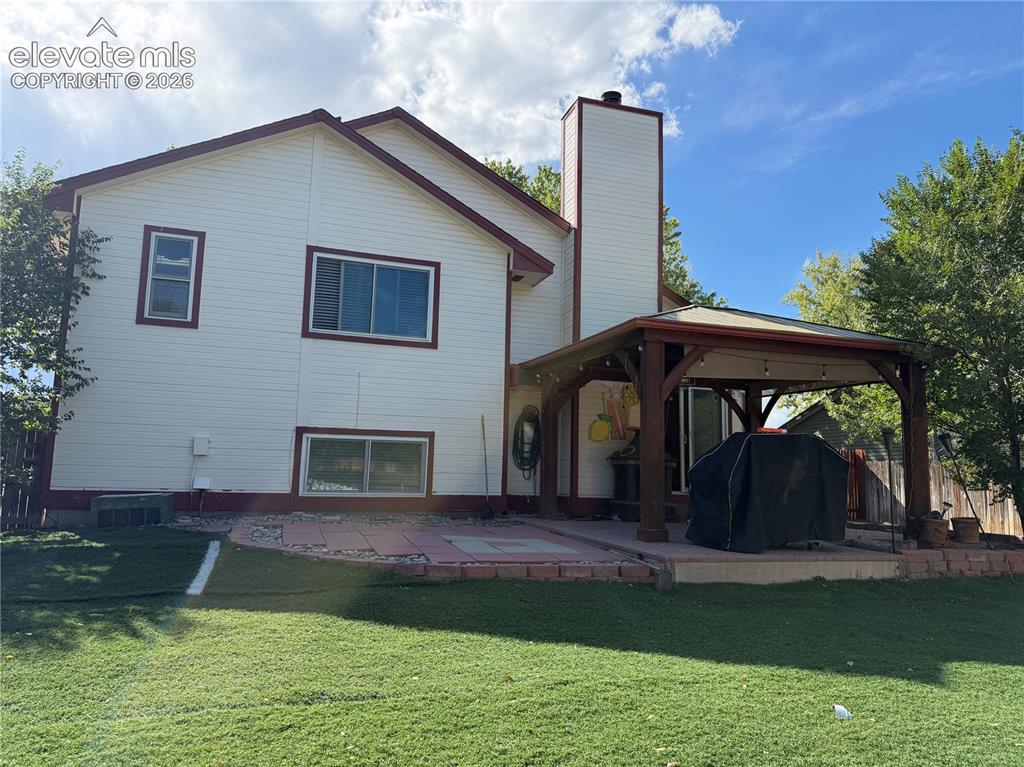Image 19 of 21: Expansive backyard featuring a large paved patio, a wood-frame covered gaze