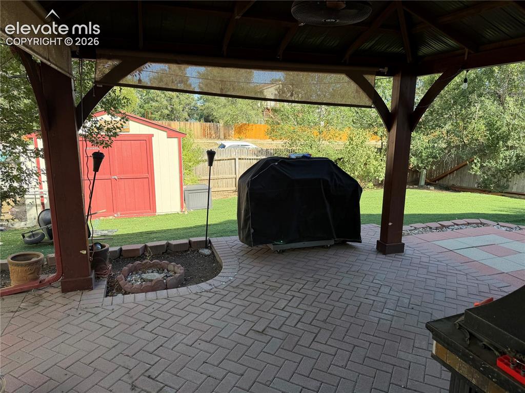 Image 20 of 21: Covered patio with a multi-tone paver floor, a built-in fire pit, and a det