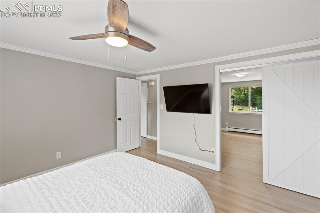Image 12 of 33: Bedroom featuring crown molding, light wood-style flooring, a baseboard hea