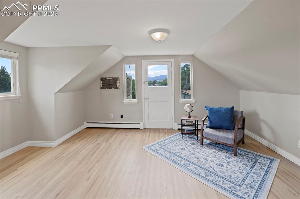 Image 15 of 33: Sitting room featuring wood finished floors, a baseboard radiator, vaulted