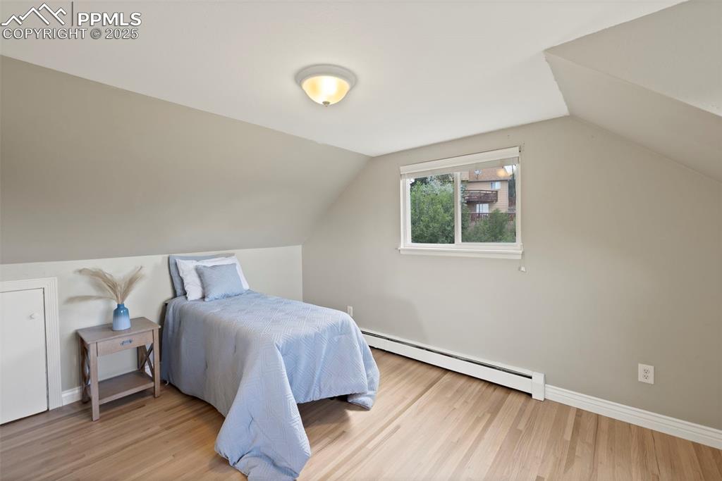 Image 19 of 33: Bedroom featuring a baseboard heating unit, lofted ceiling, and wood finish
