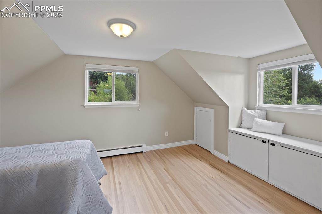 Image 20 of 33: Bedroom featuring light wood finished floors, baseboard heating, and vaulte