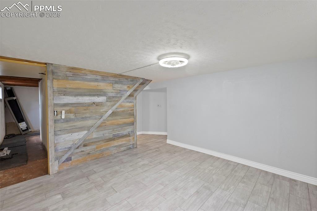 Image 23 of 33: Basement with a textured ceiling, wood finished floors, and wood walls