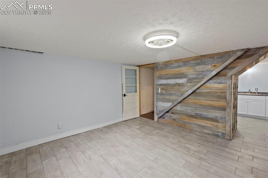 Image 24 of 33: Finished below grade area with a textured ceiling, wood finished floors, an
