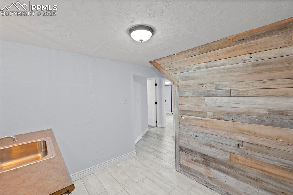 Image 26 of 33: Hall featuring wooden walls, a textured ceiling, and wood finish floors