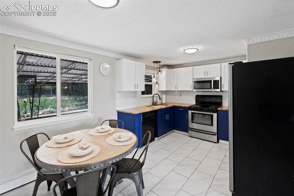 Image 5 of 33: Kitchen with blue cabinets, appliances with stainless steel finishes, baseb