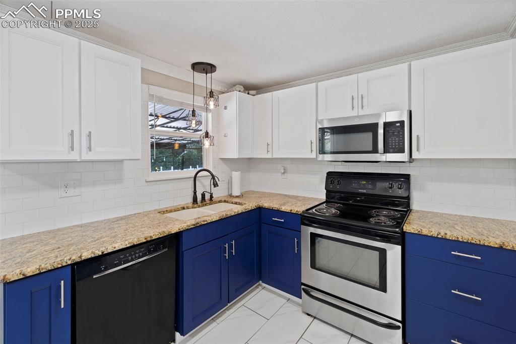 Image 7 of 33: Kitchen with appliances with stainless steel finishes, blue cabinets, decor