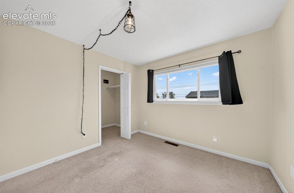 Image 17 of 25: Neutral tone wall paint, light-toned carpeting, double-pane window, and whi
