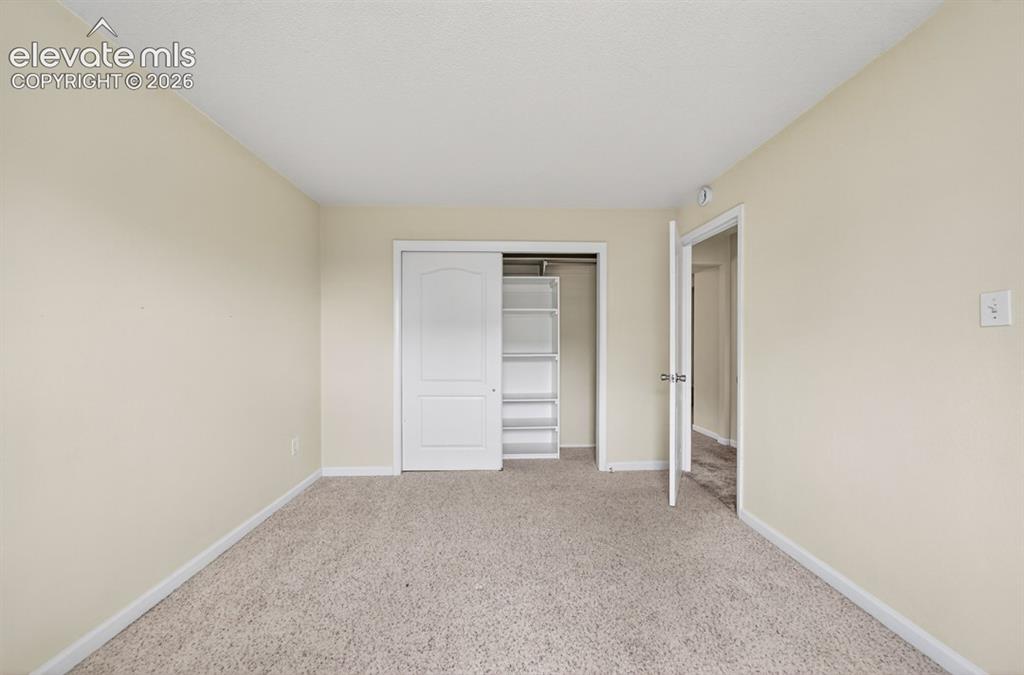 Image 20 of 25: Neutral tone wall paint, textured carpet flooring, sliding closet doors, bu