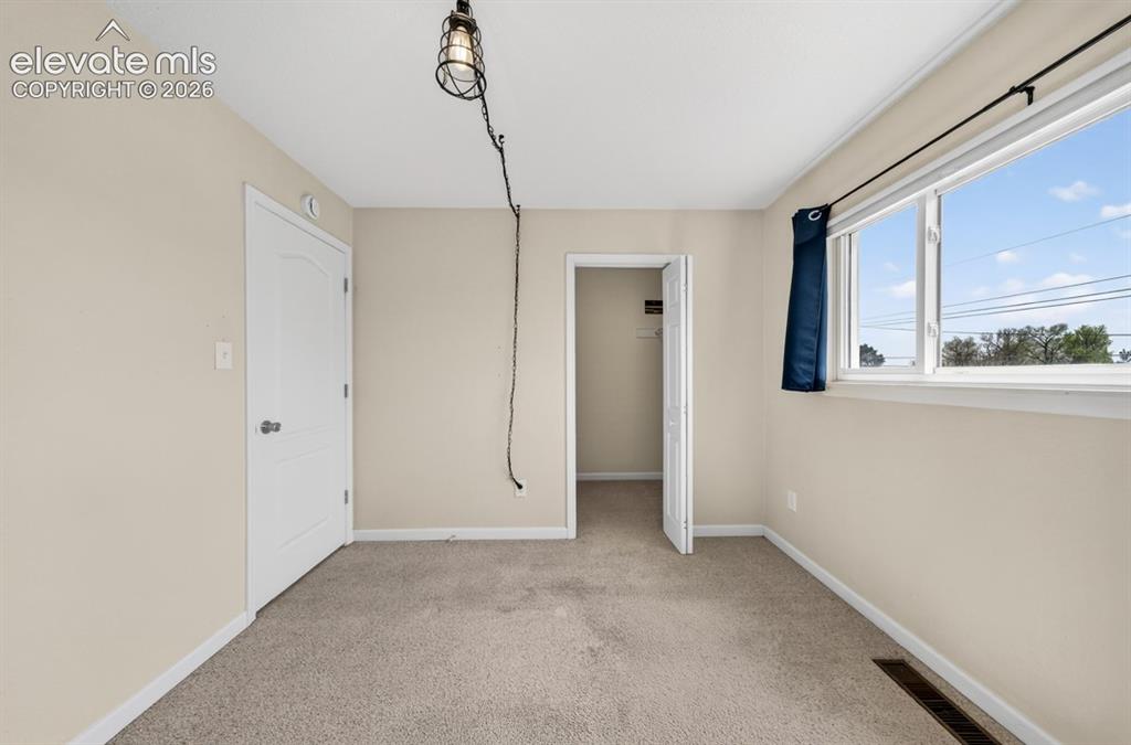 Image 21 of 25: Textured carpeting, neutral wall paint, a white-framed window, and a recess