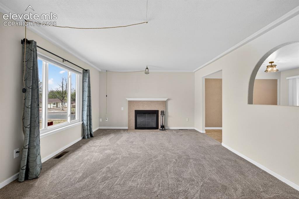 Image 4 of 25: Recessed fireplace with a stone surround and white mantle, carpet flooring,