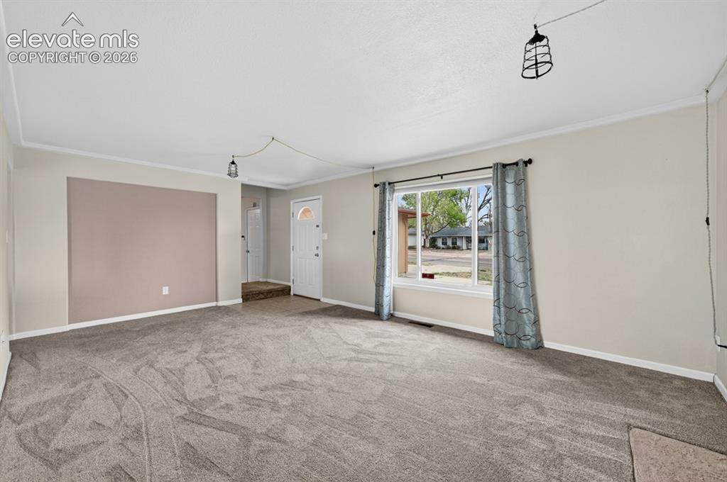 Image 5 of 25: Spacious room featuring neutral carpeting, light-toned walls, and a large f