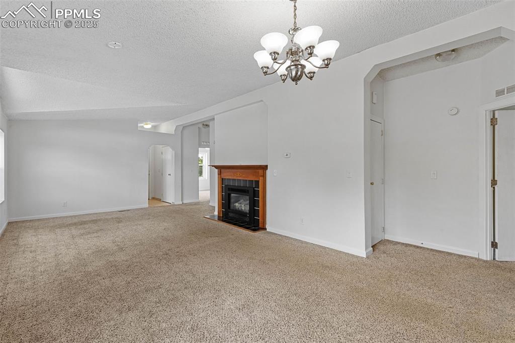 Image 14 of 24: Unfurnished living room featuring arched walkways, light carpet, a textured