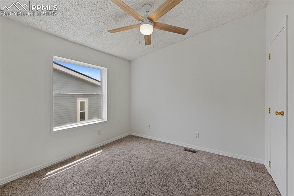 Image 19 of 24: Carpeted empty room featuring a ceiling fan and a textured ceiling