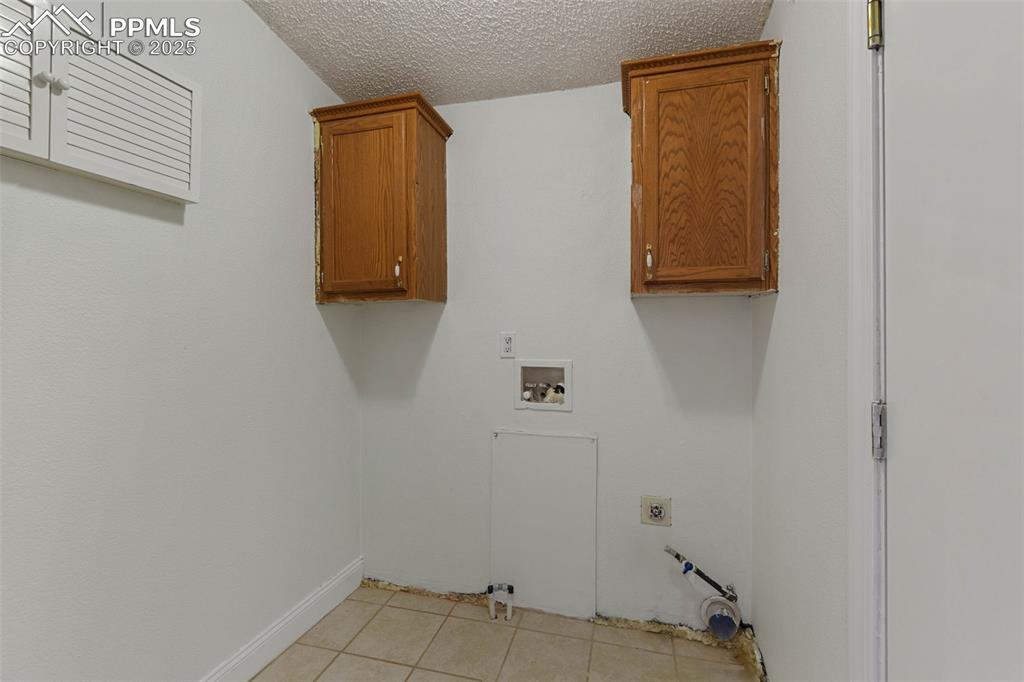Image 22 of 24: Laundry area featuring hookup for a washing machine, light tile patterned f