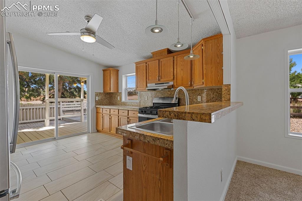 Image 8 of 24: Kitchen with a textured ceiling, stainless steel appliances, a peninsula, d