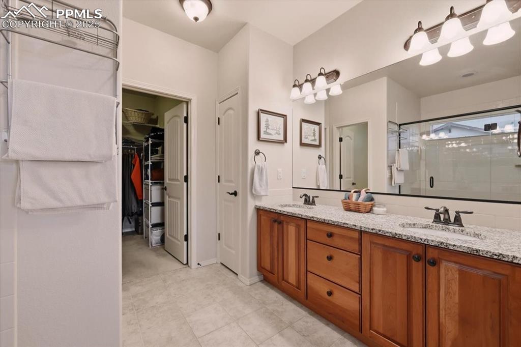 Image 15 of 26: Full bathroom with a stall shower, double vanity, and a spacious closet