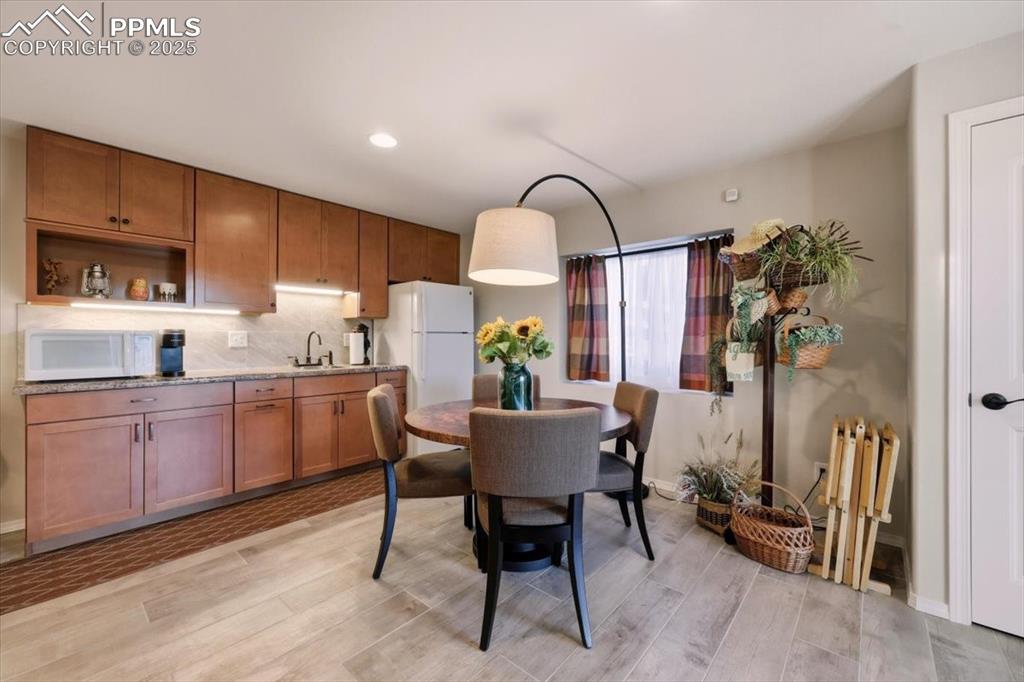 Image 18 of 26: Dining space with light wood finished floors and recessed lighting