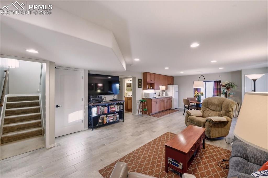 Image 19 of 26: Cozy rec space area in the basement with stairway, light wood-style floors,