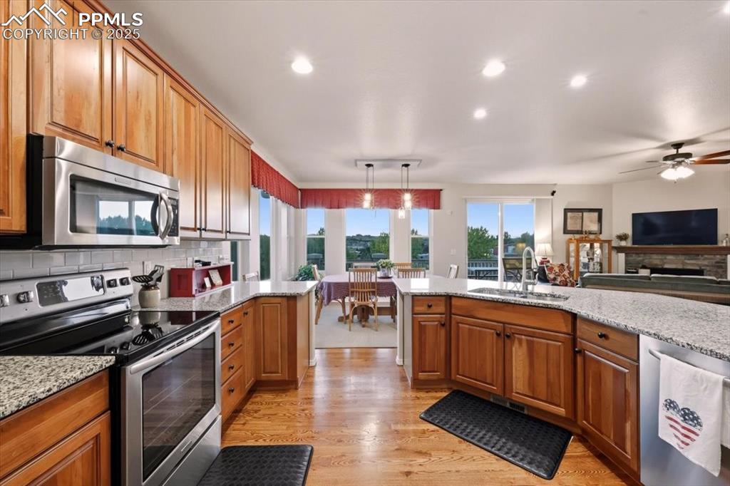 Image 8 of 26: Kitchen featuring stainless steel appliances, tasteful backsplash, brown ca
