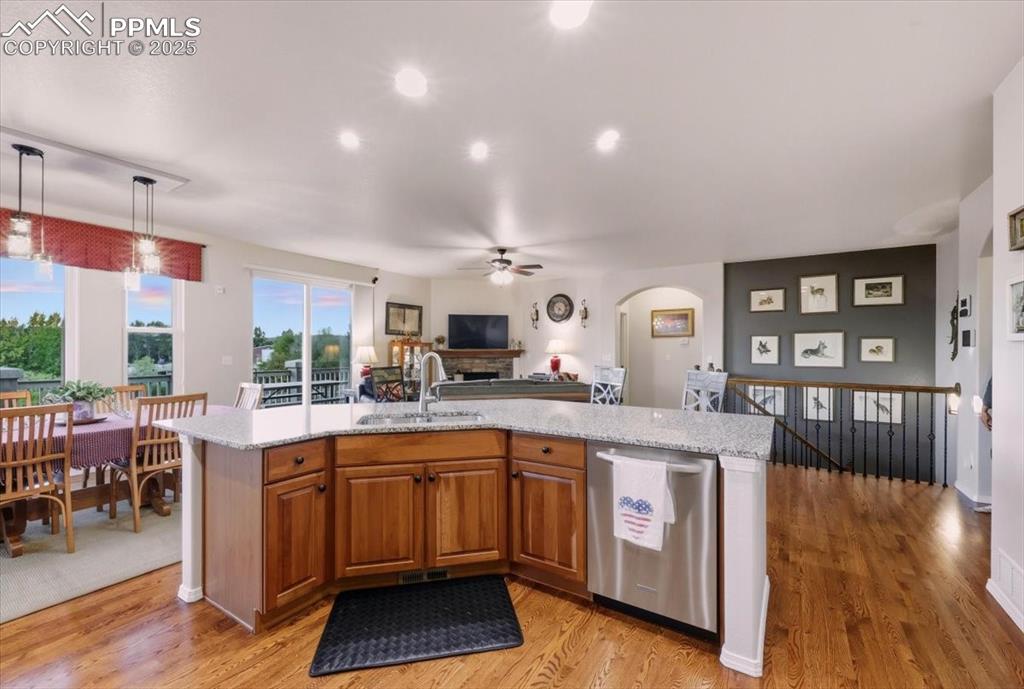 Image 9 of 26: Kitchen with brown cabinets, stainless steel dishwasher, an island with sin