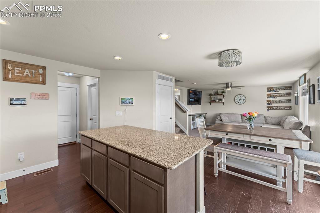 Image 10 of 33: Kitchen featuring a kitchen island, light stone counters, recessed lighting