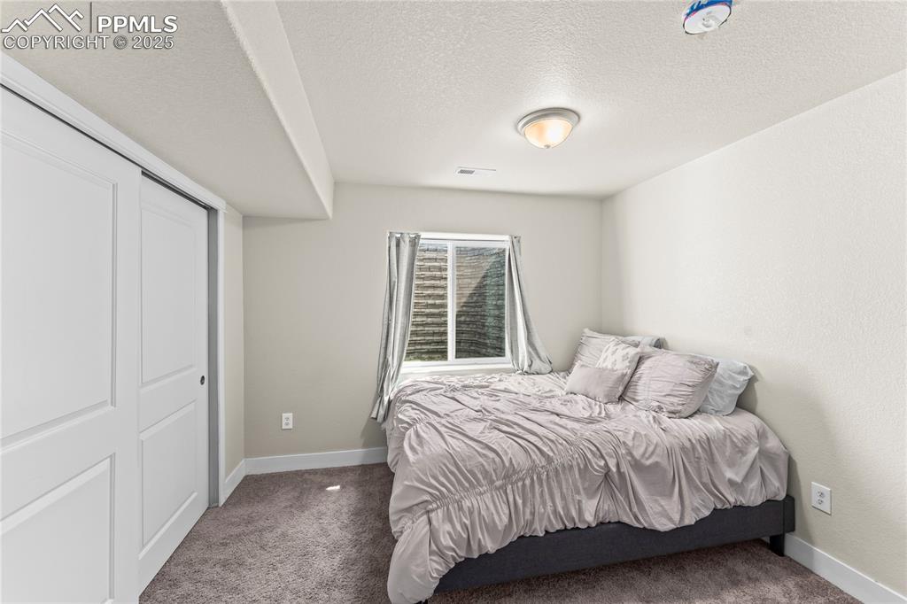 Image 16 of 33: Carpeted bedroom with a textured ceiling and a closet