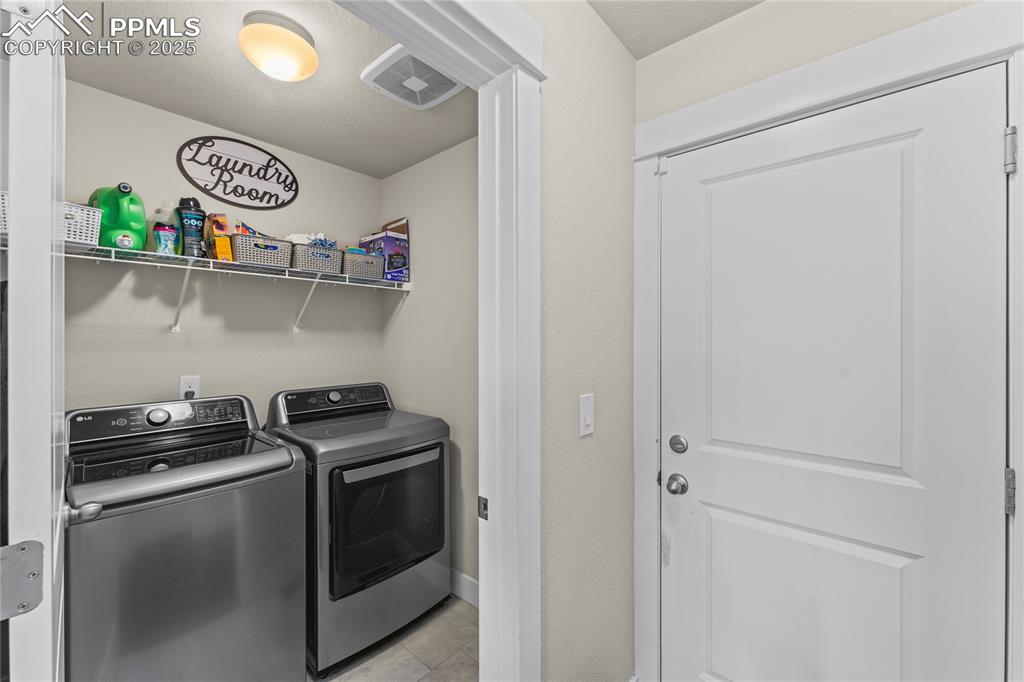 Image 18 of 33: Laundry area with washer and clothes dryer and light tile patterned floorin