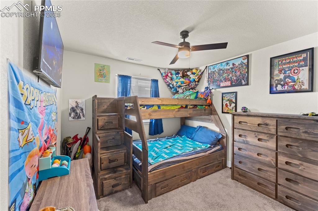 Image 20 of 33: Bedroom featuring a textured ceiling, light colored carpet, and ceiling fan