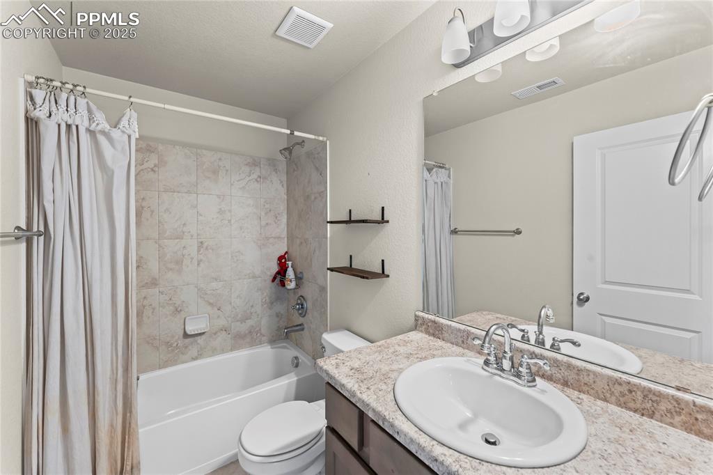 Image 23 of 33: Bathroom featuring shower / bath combination with curtain and vanity