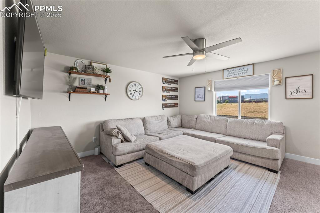 Image 3 of 33: Living area with carpet flooring, a textured ceiling, and ceiling fan