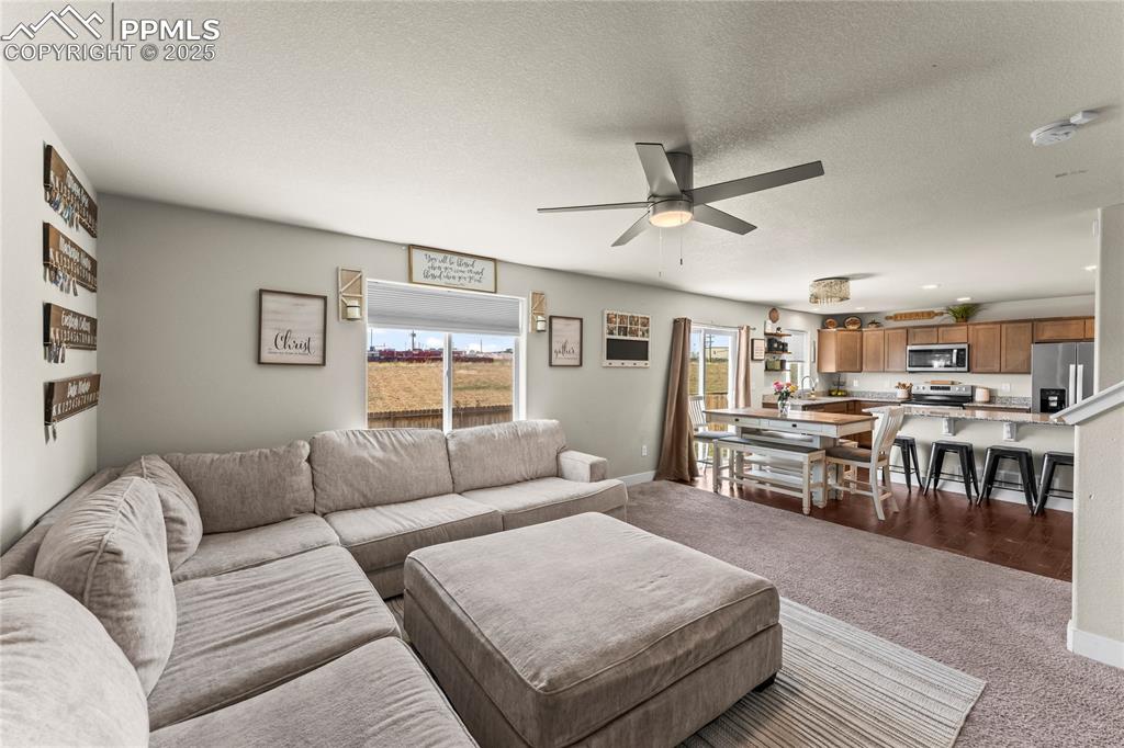 Image 5 of 33: Carpeted living area featuring a textured ceiling and ceiling fan