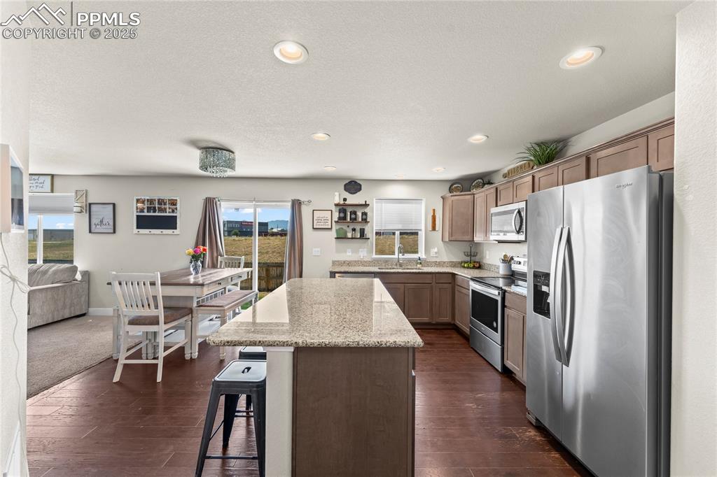 Image 7 of 33: Kitchen featuring stainless steel appliances, light stone countertops, a ki