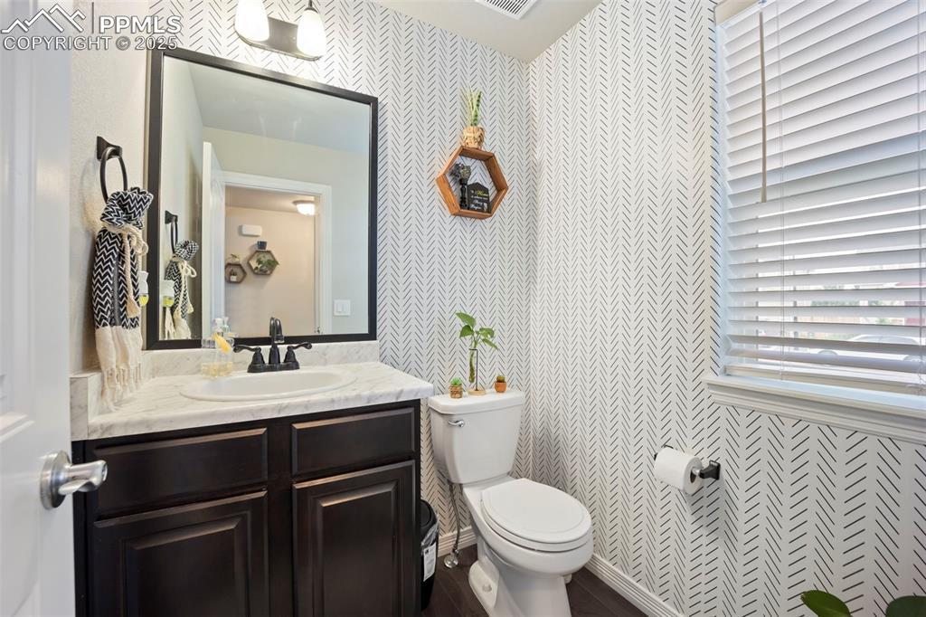 Image 11 of 45: Half bath with vanity and wallpapered walls