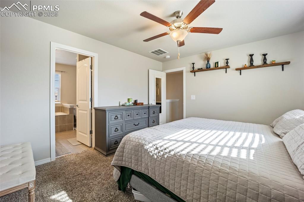 Image 18 of 45: Bedroom featuring ceiling fan, carpet, and ensuite bath