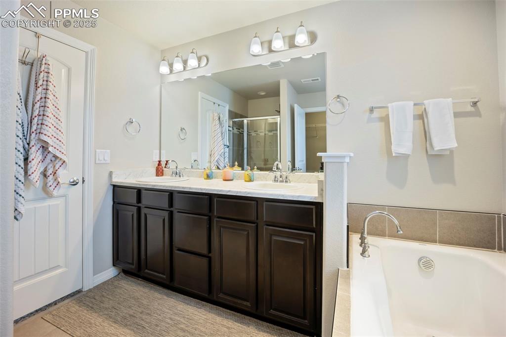 Image 20 of 45: Bathroom featuring double vanity, a stall shower, and a bath