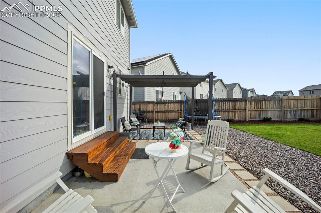 Image 25 of 45: Fenced backyard featuring a trampoline, a patio area, and a residential vie