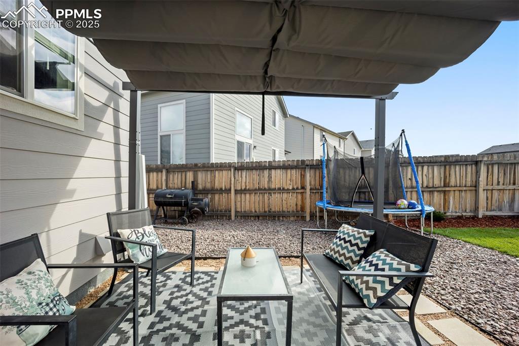 Image 26 of 45: Fenced backyard with a patio area, a trampoline, an outdoor hangout area, a