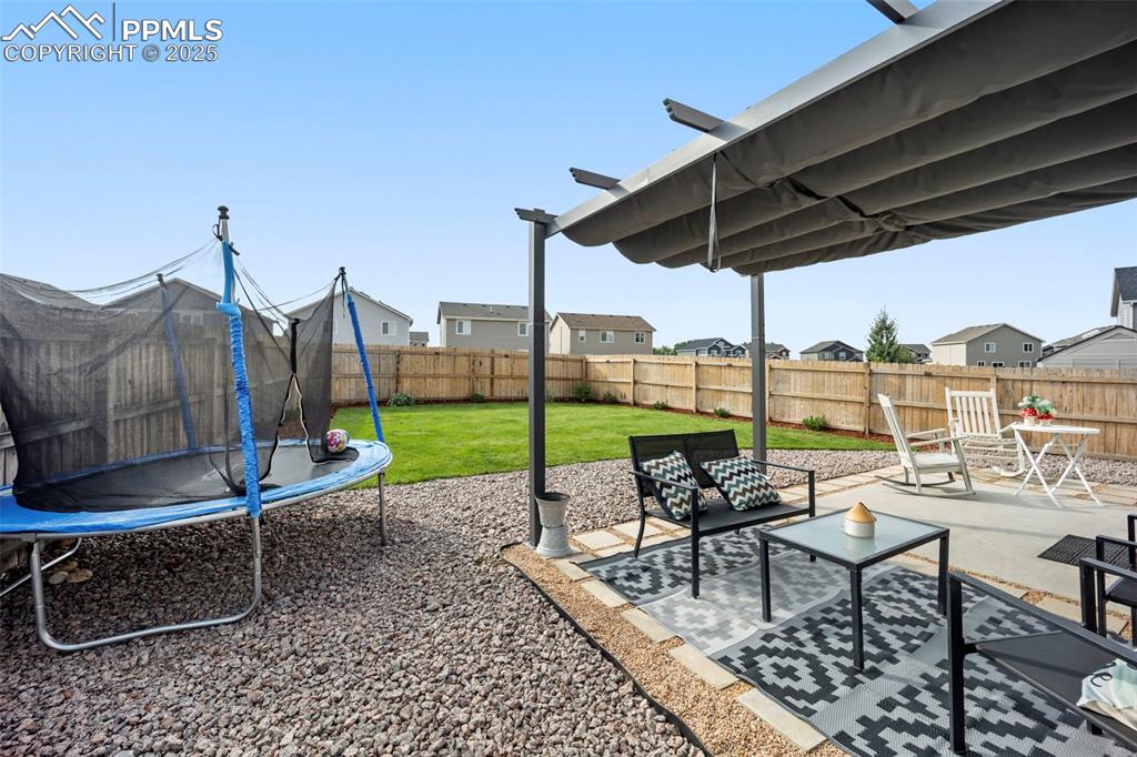 Image 27 of 45: Fenced backyard featuring a trampoline, a patio, a residential view, and a
