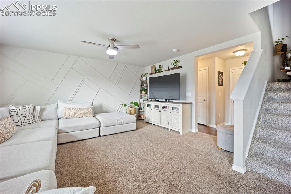 Image 6 of 45: Carpeted living area featuring stairs and a ceiling fan