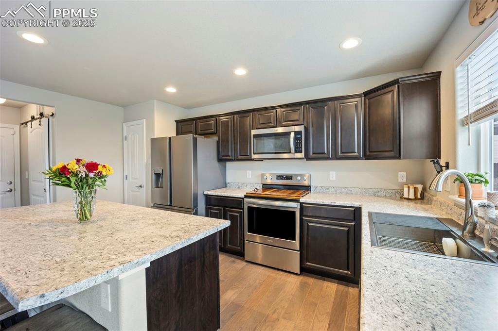 Image 7 of 45: Kitchen with dark brown cabinets, appliances with stainless steel finishes,