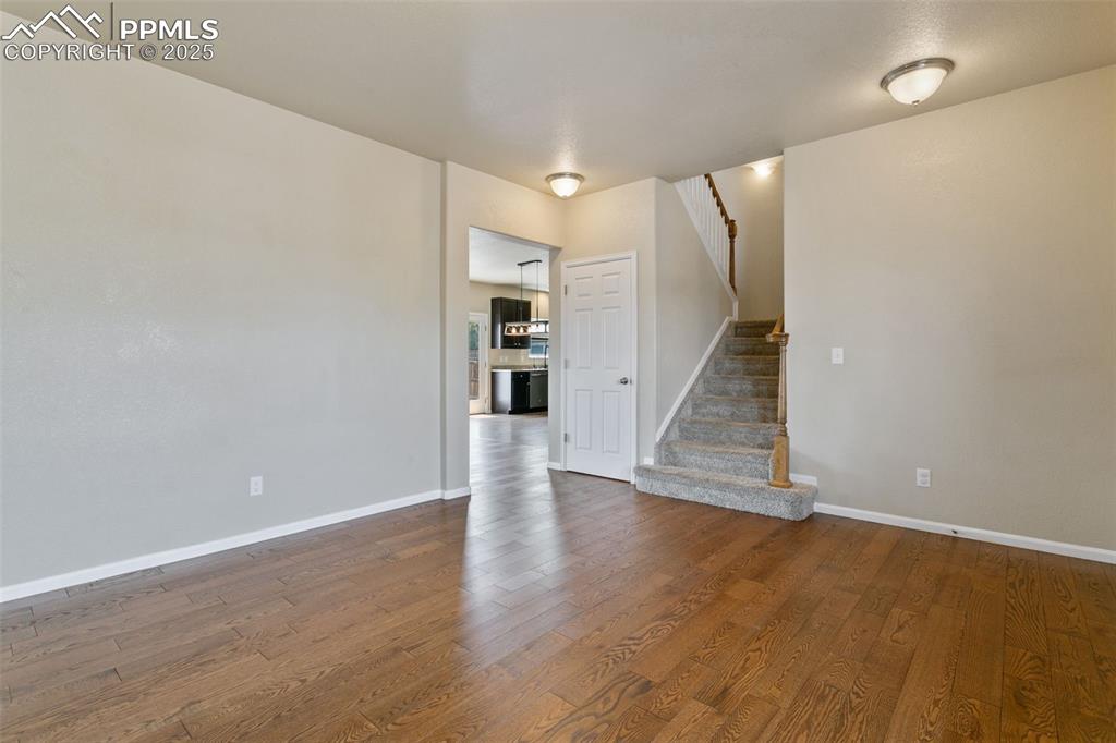 Image 12 of 41: Unfurnished living room with wood finished floors and stairway